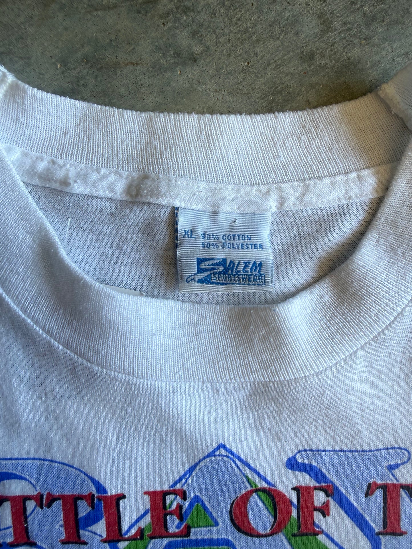 Close-up of the inside neck of a white Salem Silky Dolls t-shirt, showing the brand tag and the top of a colorful graphic print.